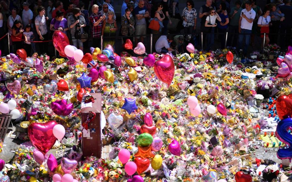 A carpet of messages of support and floral tributes to the victims of the Manchester attack lies in St Ann's Square in Manchester - Credit: BEN STANSALL/AFP/Getty Images