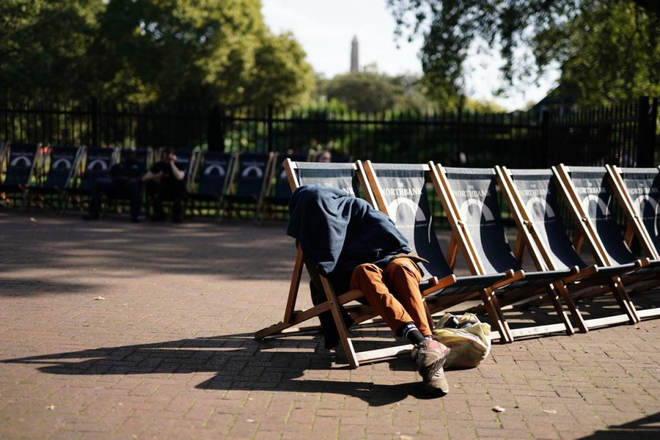 A man covers himself while sitting on a deckchair in Victoria Embankment Gardens, London (Jordan Pettitt / PA Wire)