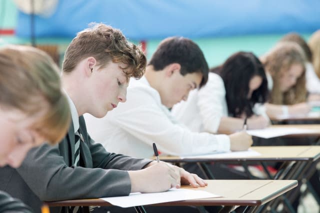 Focused middle school students taking examination at desks