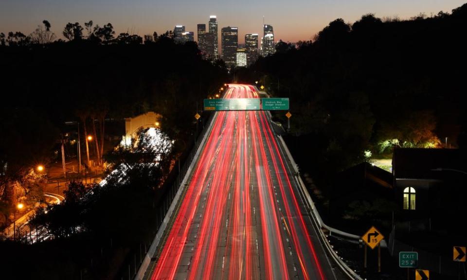 Vehicle lights are blurred in a long exposure as they make their way along the 110 freeway at dusk in Los Angeles, California