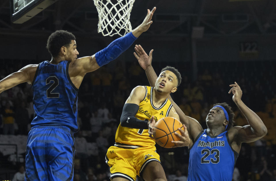 Wichita State's Xavier Bell goes up a for a shot against Memphis defenders Malcolm Dandridge, right, and Nicholas Jourdain, left, during the first half of an NCAA college basketball game, Sunday, Jan. 14, 2024, in Wichita, Kan. (Travis Heying/The Wichita Eagle via AP)