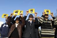 People shield their faces with specially-constructed cards showing the four-finger symbol of Rabaa, to show their support for ousted Egyptian President Mohamed Mursi, as they observe a solar eclipse in Amman November 3, 2013. Sky watchers across the world are in for a treat Sunday as the final solar eclipse of 2013 takes on a rare hybrid form. REUTERS/Muhammad Hamed (JORDAN - Tags: SOCIETY ENVIRONMENT)