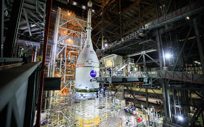 An Orion crew capsule, covered by a protective launch shroud, is mounted atop a Space Launch System heavy lift booster inside NASA's Vehicle Assembly Building at the Kennedy Space Center. An unpiloted test flight beyond the moon and back is planned for next year. / Credit: NASA