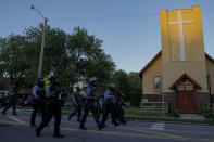 FILE - St. Paul Police officers move in on a crowd past a church, Thursday, May 28, 2020, in St. Paul, Minn. The Rev. Charles Graham and other Twin Cities faith leaders who minister to communities historically ravaged by racial injustice know their neighborhoods are also the most vulnerable to poverty and crime. Most of the worst looting and vandalism this week struck long-established Native and African American areas that more recently became home to large groups of Hmong, Somali and Latino migrants.(AP Photo/Julio Cortez)