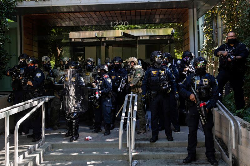 Portland police officers and DHS officers stand outside a Federal building in Portland