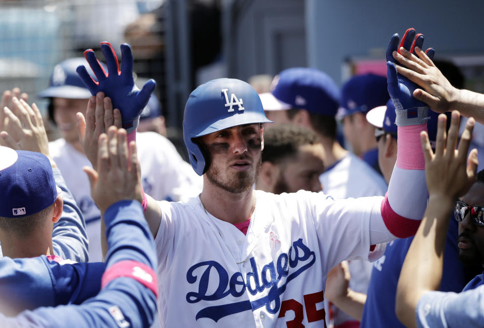 Los Angeles Dodgers' Cody Bellinger gets high-fives in the dugout after scoring on a sacrifice fly ball from Corey Seager during the second inning of a baseball game against the Washington Nationals, Sunday, May 12, 2019, in Los Angeles. (AP Photo/Marcio Jose Sanchez)