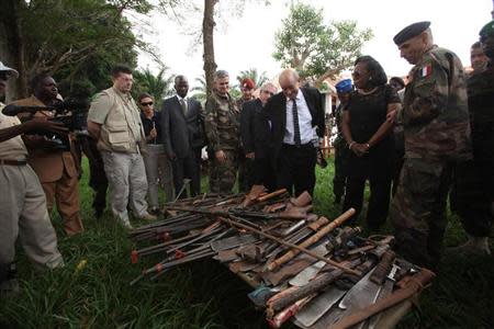 French Defense Minister Jean Yves-Le Drian (C) and Central African Republic's interim President Catherine Samba Panza (2nd R) look at seized weapons during his visit to Mbaiki, about 105 km (65 miles) away from Bangui, February 12, 2014. Picture taken February 12, 2014. REUTERS/Media Coulibaly