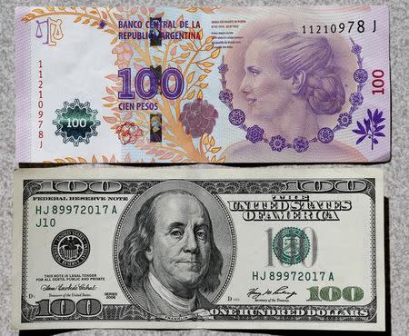 An Argentine 100 pesos bank (above) note, featuring an image of former first lady Eva Peron, is displayed next to a U.S. 100 dollar note in Buenos Aires September 17, 2014. REUTERS/Enrique Marcarian