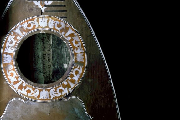 A mandolin made by G.Filano, shown here under UV light. The light causes fluorescence, particularly of the sound hole decoration. The reddish color is characteristic of the resin of the false inlay, which seems to be made mostly of shellac.