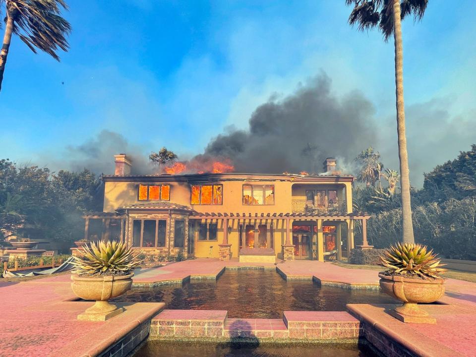 mansion with decorative pool plaza burning in smoky wildfire