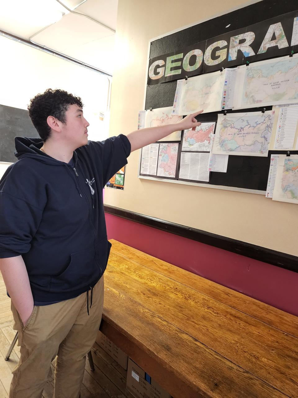 Global Learning Charter School junior Ty Velez, 17, points out the details of his multi-layered map focusing on the area of Russia and Ukraine. Aside from geographic features of the region, the map addresses a number of aspects such as changes in national borders from the time of the Soviet Union to now.