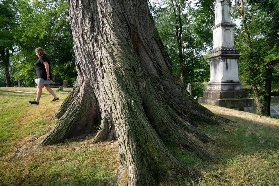 Joannie Capuano, 63, executive director of the historic Elmwood Foundation, walks by an elm tree that is on the grounds of the historic Elmwood Cemetery in Detroit on Tuesday, July, 5, 2022. This particular elm dates to 250-300 years old.