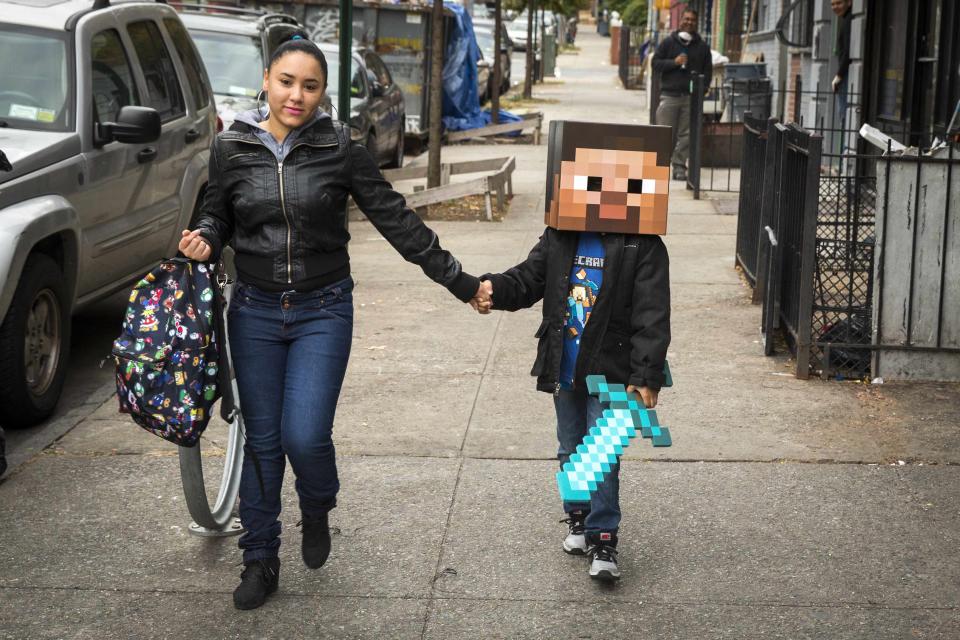 RNPS - REUTERS NEWS PICTURE SERVICE - PICTURES OF THE YEAR 2014 - ODDLY A woman walks her child to school as he is dressed as a character from Minecraft in New York in this October 31, 2014 file photo. REUTERS/Lucas Jackson/Files (UNITED STATES - Tags: SOCIETY)