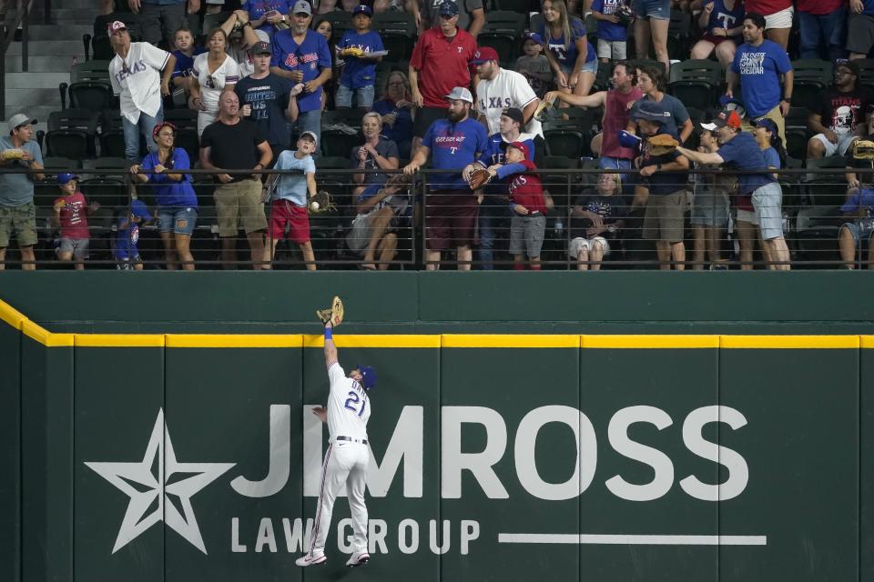 Texas Rangers' David Dahl (21) and a young fan make a play for a home run ball hit by Oakland Athletics' Jed Lowrie in the fourth inning of a baseball game in Arlington, Texas, Saturday, July 10, 2021. (AP Photo/Tony Gutierrez)