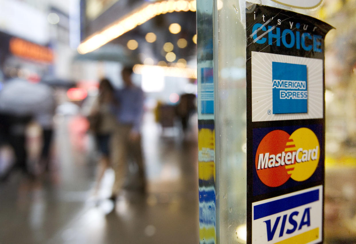 Signs for American Express, Master Card and Visa credit cards are shown on a New York store's door. The stress from deepening debt is becoming a major pain in the neck for millions of Americans. (Credit: Mark Lennihan)