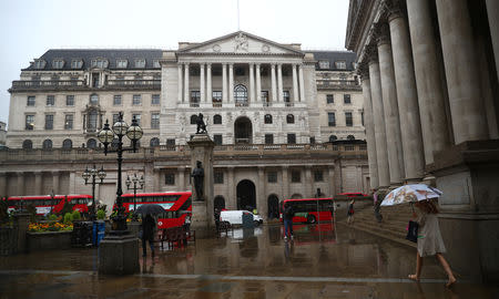 Pedestrians shelter under umbrellas in front of the Royal Exchange and the Bank of England, in London, Britain August 16, 2018. REUTERS/ Hannah McKay