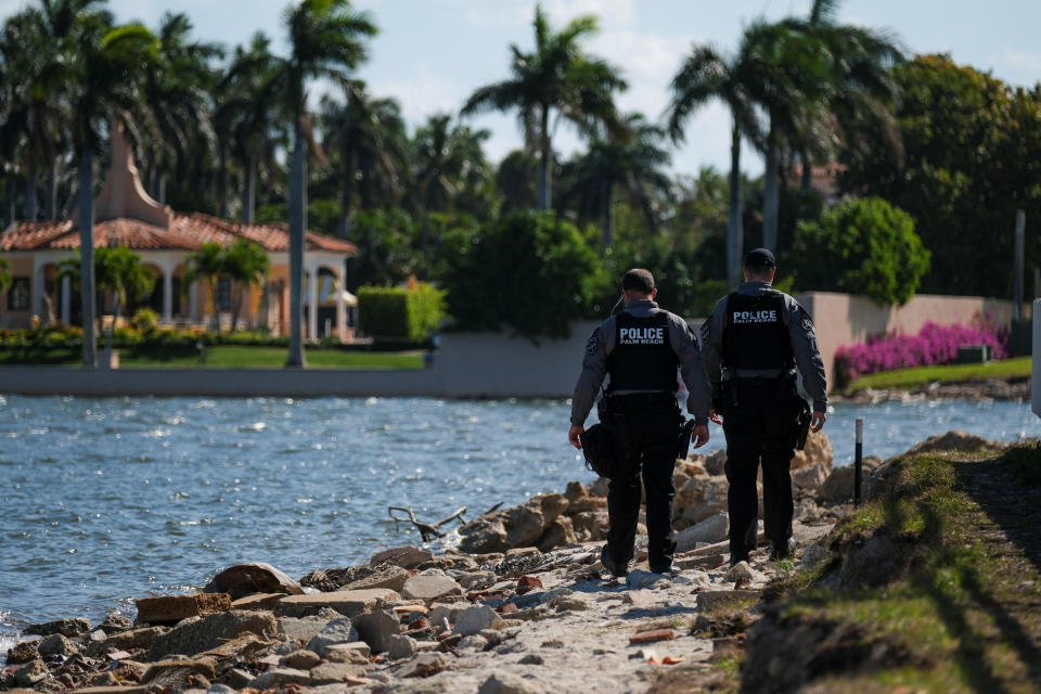 Two police officers patrol a rocky area adjacent to the water next to Donald Trump's Mar-a-Lago resort in Palm Beach, Fla.