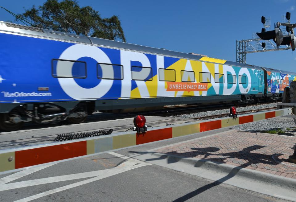 An advertisement wrap for Orlando is seen on the side of a passenger car as a Brightline train heads north through Fort Pierce from Miami to Orlando on their first day of passenger service.