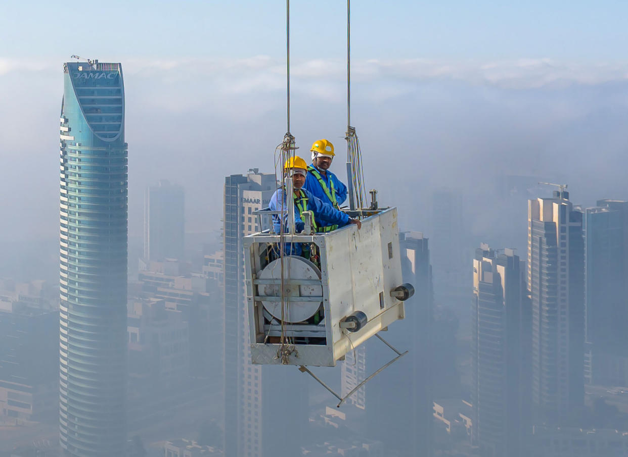 The pair were given an unimpeded view of the city through the morning fog as they went about their work. (SWNS)