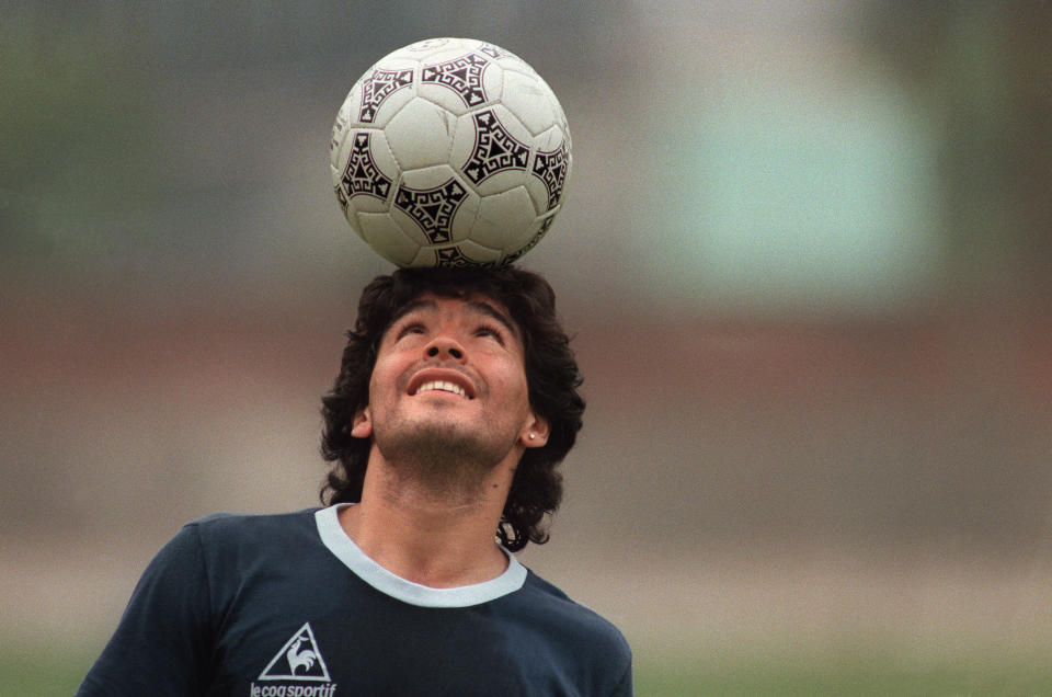 Diego Maradona balances a soccer ball on his head as he walks off the practice field following the Argentina national team practice session ahead of the 1986 World Cup. (PHOTO: Jorge Duran/AFP via Getty Images)