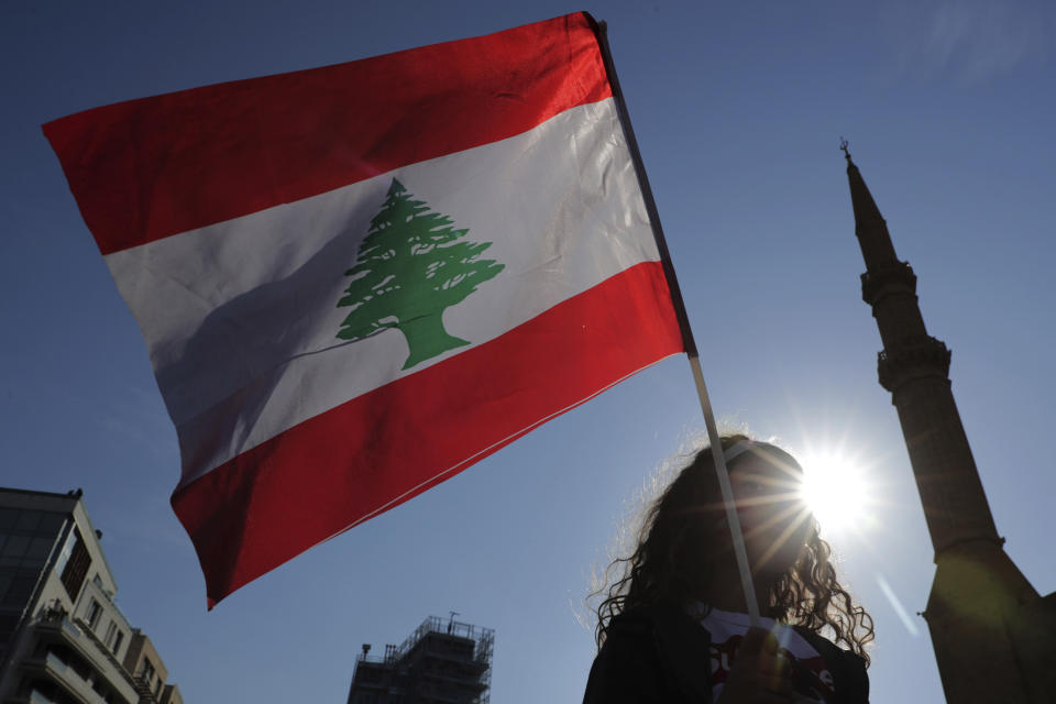 An anti-government protester holds the Lebanese national flag during separate civil parade at the Martyr square, in downtown Beirut, Lebanon, Friday, Nov. 22, 2019. Protesters gathered for their own alternative independence celebrations, converging by early afternoon on Martyrs' square in central Beirut, which used to be the traditional location for the official parade. Protesters have occupied the area, closing it off to traffic since mid-October. (AP Photo/Hassan Ammar)