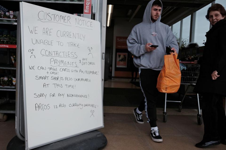 A handwritten sign outside a Sainsbury’s store in Cobham informs customers of technical problems (PA Wire)