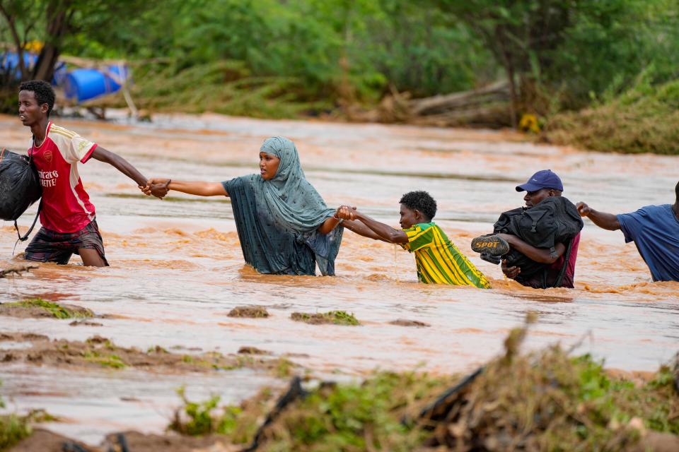 Residents cross a road damaged during flooding in Tana River county in Kenya.