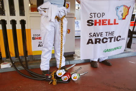 A member of Greenpeace is chained to a gas pump at a Shell gas station during a protest in Zurich, June 30, 2015. REUTERS/Arnd Wiegmann