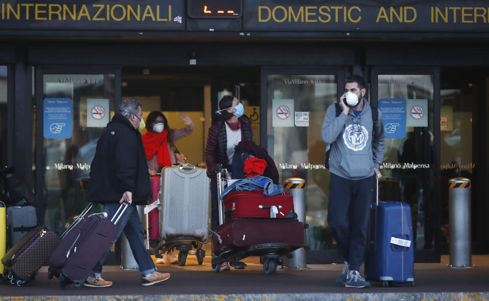 People walk upon arrival at the Malpensa airport of Milan, Italy, Sunday, March 22, 2020. For most people, the new coronavirus causes only mild or moderate symptoms. For some it can cause more severe illness, especially in older adults and people with existing health problems. (AP Photo/Antonio Calanni)