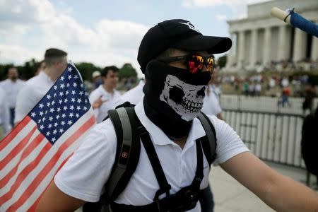 A masked demonstrator carrying a U.S. flag leaves the Lincoln Memorial after self proclaimed "White Nationalists", white supremacists and members of the "alt-right" gathered for what they called a "Freedom of Speech" rally at the memorial in Washington, June 25, 2017. REUTERS/Jim Bourg