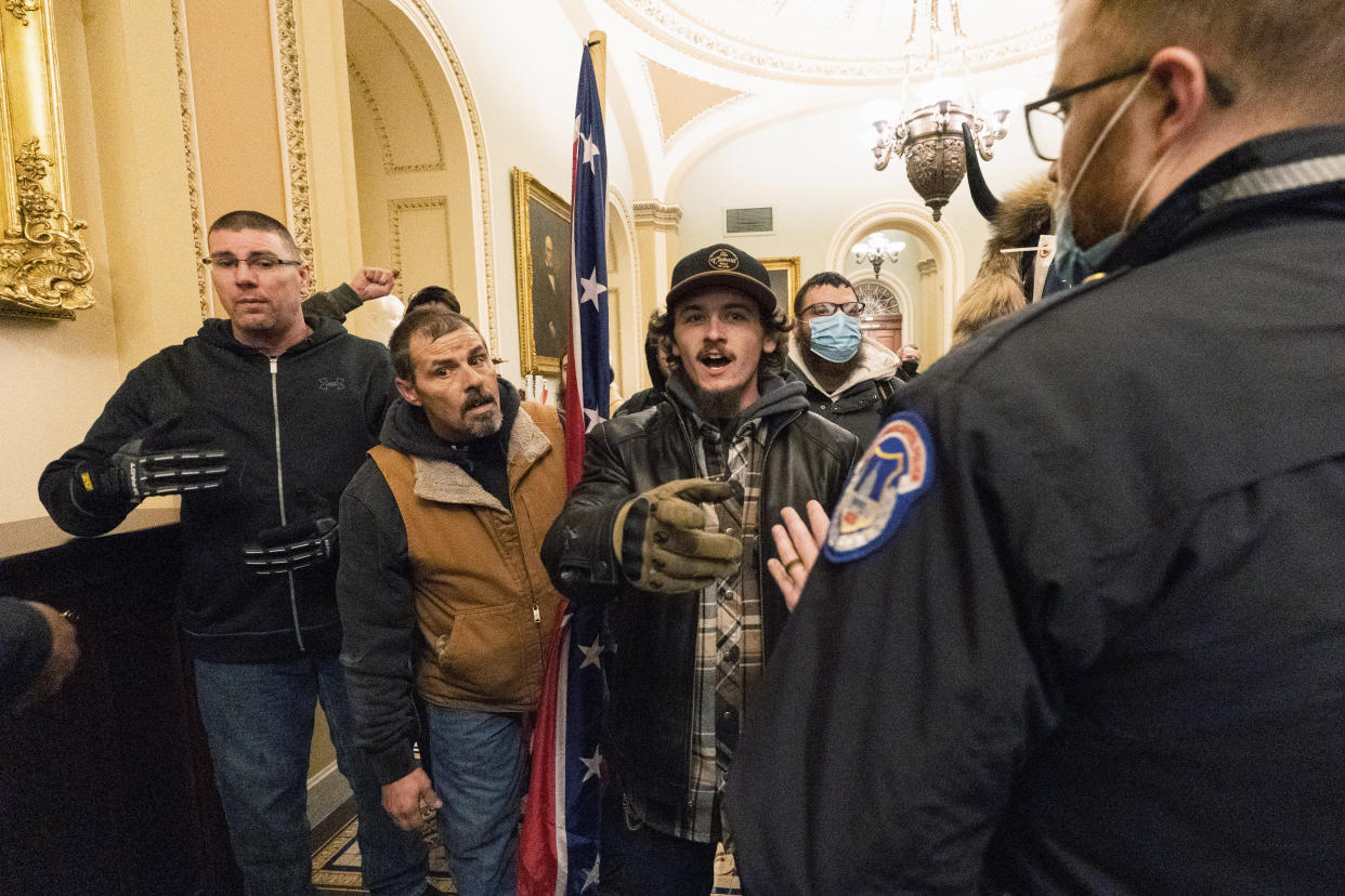 Kevin Seefried, second from left, holds a Confederate battle flag as he and other insurrectionists loyal to then President Donald Trump are confronted by U.S. Capitol Police officers outside the Senate Chamber inside the Capitol in Washington, Jan. 6, 2021. (AP)