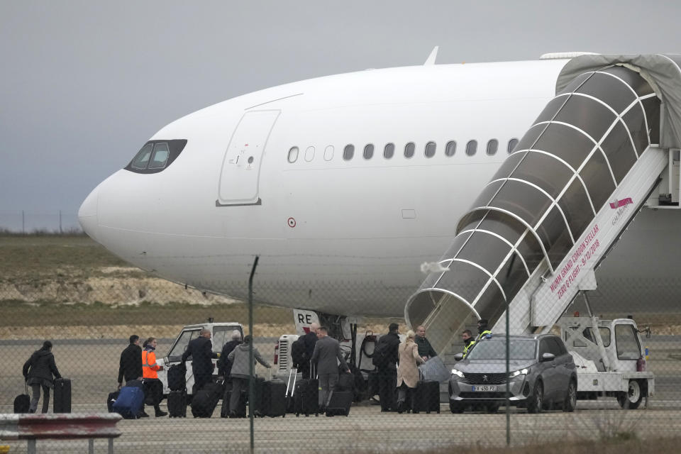 Crew members board the plane grounded by police at the Vatry airport , Monday, Dec. 25, 2023 in Vatry, eastern France. A charter plane grounded in France for a human trafficking investigation is scheduled to leave Monday for India, after an exceptional holiday ordeal that left some 300 Indians en route for Central America blocked inside a rural French airport for four days. (AP Photo/Christophe Ena)