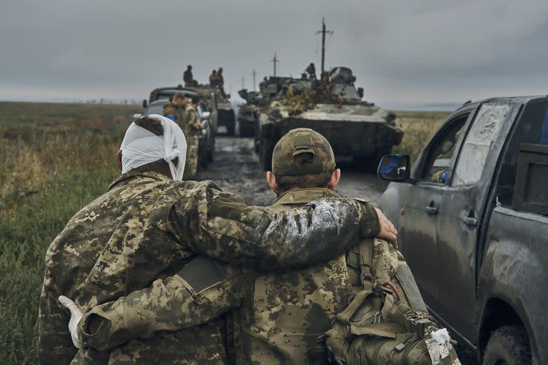 ARCHIVO - Un soldado ucraniano ayuda a un compañero herido en la carretera en el territorio liberado en la región de Járkiv, Ucrania, el lunes 12 de septiembre de 2022. Como hito, el primer aniversario de la invasión rusa en Ucrania es tan sombrío como exasperante. Es un año repleto de muerte, destrucción, pérdida y daños que se sienten mucho más allá de las fronteras de Rusia y Ucrania. (AP Foto/Kostiantyn Liberov, Archivo)