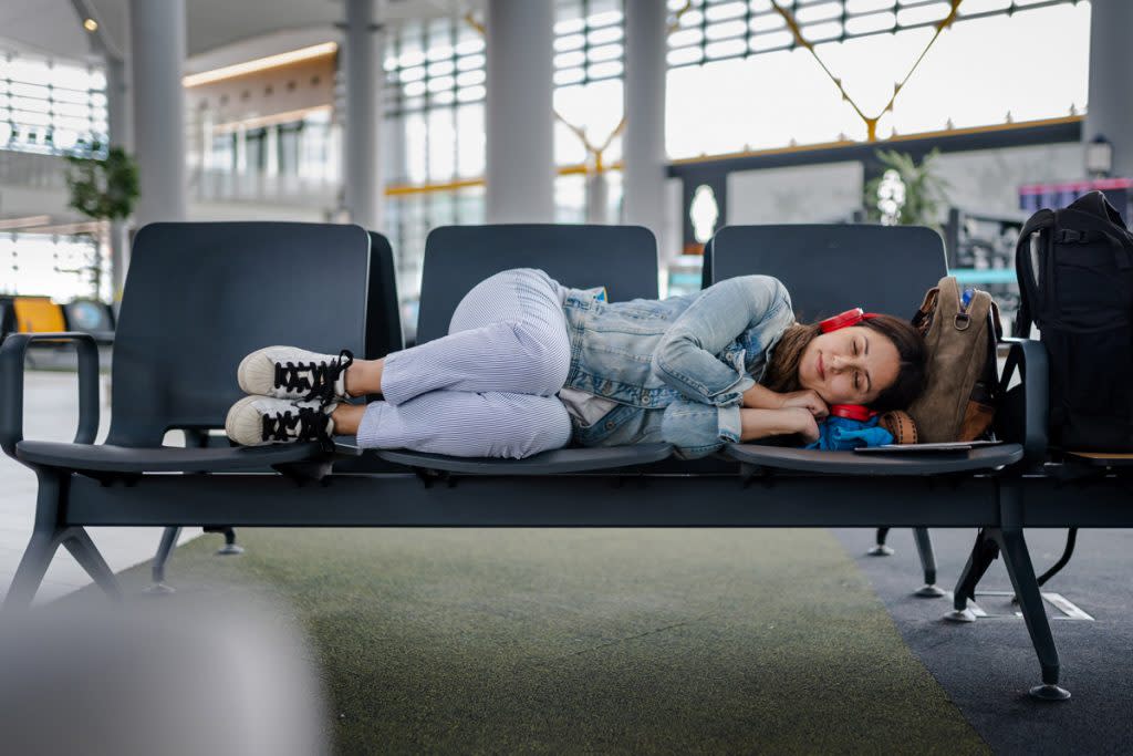 A woman sleeps during a layover at the airport. 