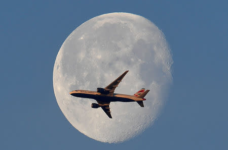 FILE PHOTO: A British Airways passenger plane flies in front of the moon above London, Britain, May 3, 2018. REUTERS/Toby Melville/File Photo