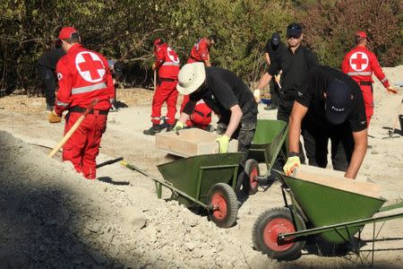 South Yorkshire police officers and members of the Greek rescue service (in red uniforms) investigate the ground while excavating a site during an investigation for Ben Needham, a 21-month-old British toddler who went missing in 1991, on the island of Kos, Greece, September 27, 2016. REUTERS/Vassilis Triandafyllou