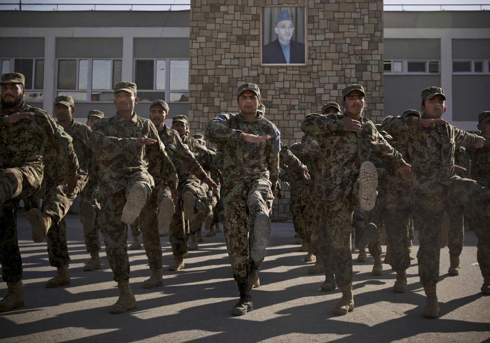 FILE - In this Nov. 26, 2013 file photo Afghan Army soldiers exercise under a picture of Afghanistan's President Hamid Karzai at a training facility in the outskirts of Kabul, Afghanistan. Afghans go to the polls April 5, 2014 to choose a new president, and that in itself may one day be considered Karzai’s greatest achievement. (AP Photo/Anja Niedringhaus, File)