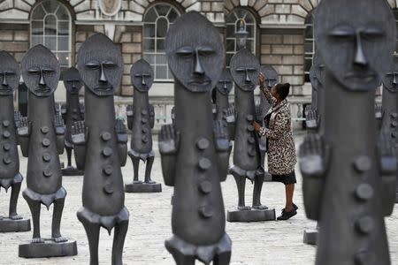 An assistant poses with sculptures "Black and Blue: The invisible Man and the Masque of Blackness", by artist Zak Ove, at Somerset House in London, Britain October 4, 2016. REUTERS/Stefan Wermuth