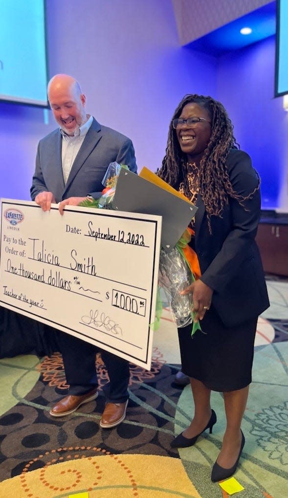 Talicia Smith, a teacher at Douglas Byrd Middle School. grins widely as Adam Fellers looks on, after Smith was named the Cumberland County school district's Teacher of the Year. Fellers is with Lafayette Ford, a sponsor of the event.