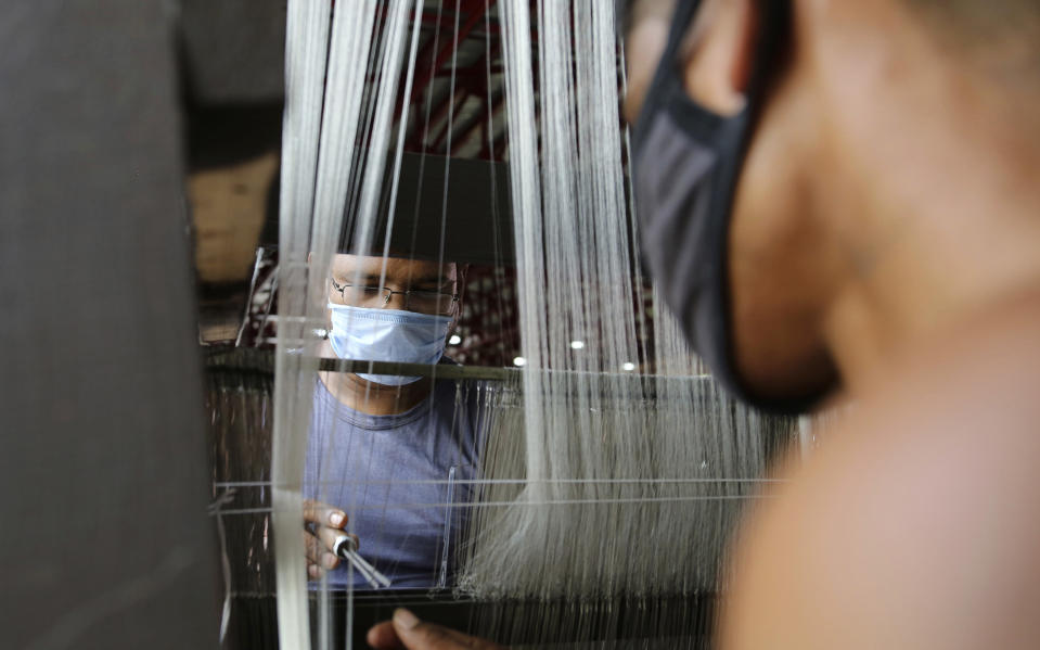 People wear face masks and work at a silk factory on the outskirts of Jammu, India, Friday, Aug. 14, 2020. Sericulture is a major economic activity in hundreds of villages in the Jammu and Kashmir region. (AP Photo/ Channi Aanad)