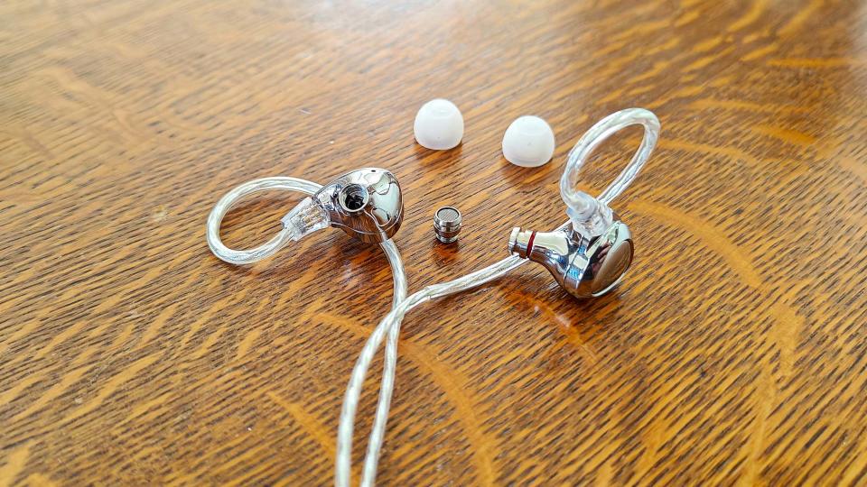 EarFun EH100 earbuds with eartips removed on a wooden table