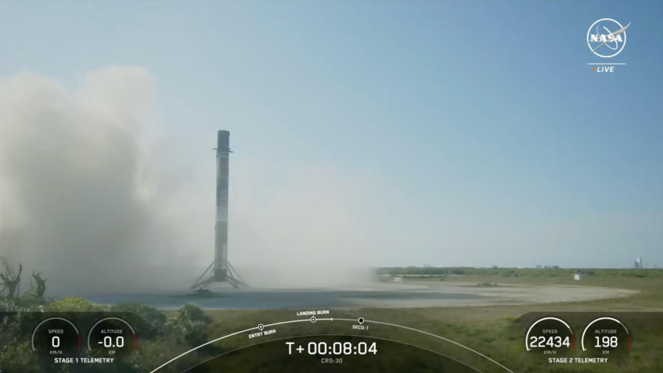 a black and white rocket rests on a dark landing pad, surrounded by exhaust and kicked-up dust