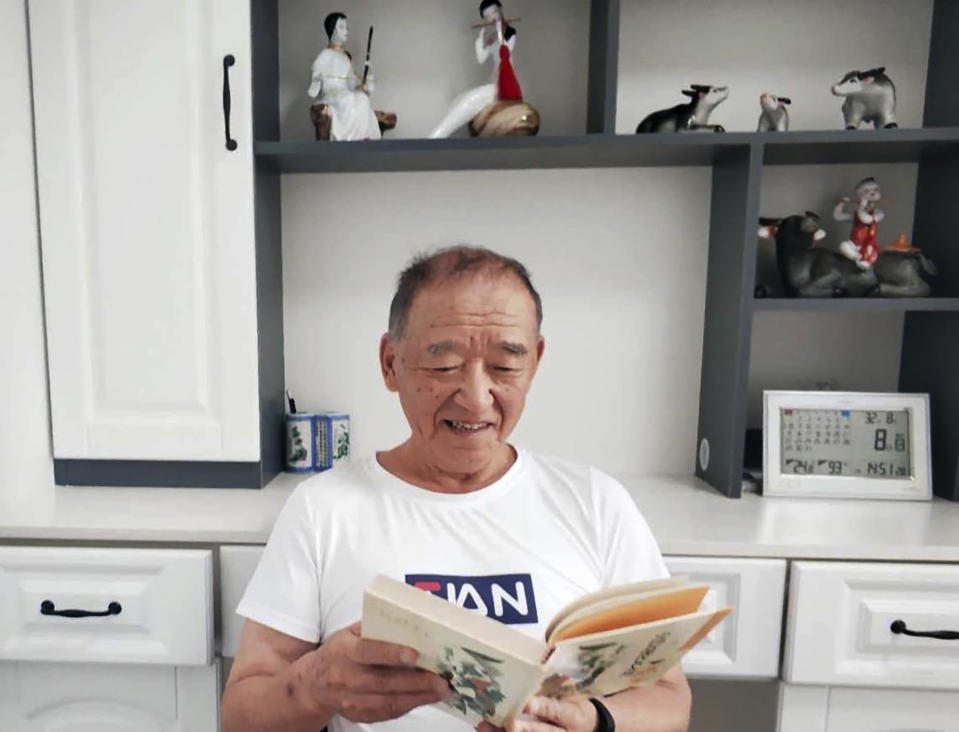 In this photo taken and released by Xi Chunmei, Xi Jingbo looks at a book at his new home in Linkou county, Mudanjiang city in northeastern China's Heilongjiang province on Aug. 8, 2020. More than 2,500 children of about 400,000 Japanese - many of them families of Imperial Army soldiers, Manchurian railway employees and farmers who had emigrated to northern China, where Japan established a wartime puppet state - were displaced or orphaned. Xi Jingbo's parents were Japanese, but he had no official record of his place and date of birth. Villagers told him he was left behind when the Japanese fled after the surrender. (Xi Chunmei via AP)