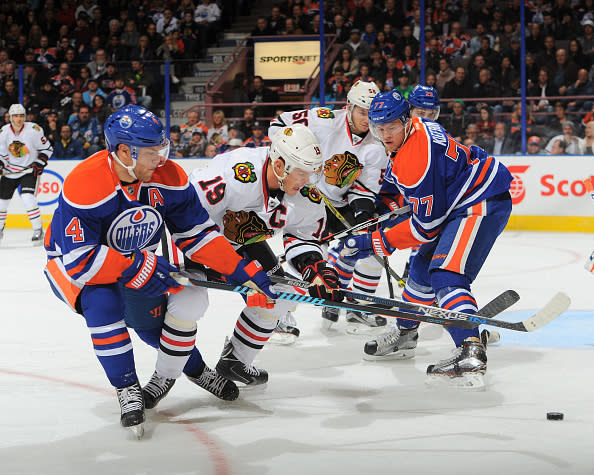 EDMONTON, AB - NOVEMBER 18: Taylor Hall #4 and Oscar Klefbom #77 of the Edmonton Oilers battle for the puck against Jonathan Toews #19 of the Chicago Blackhawks on November 18, 2015 at Rexall Place in Edmonton, Alberta, Canada. (Photo by Andy Devlin/NHLI via Getty Images)