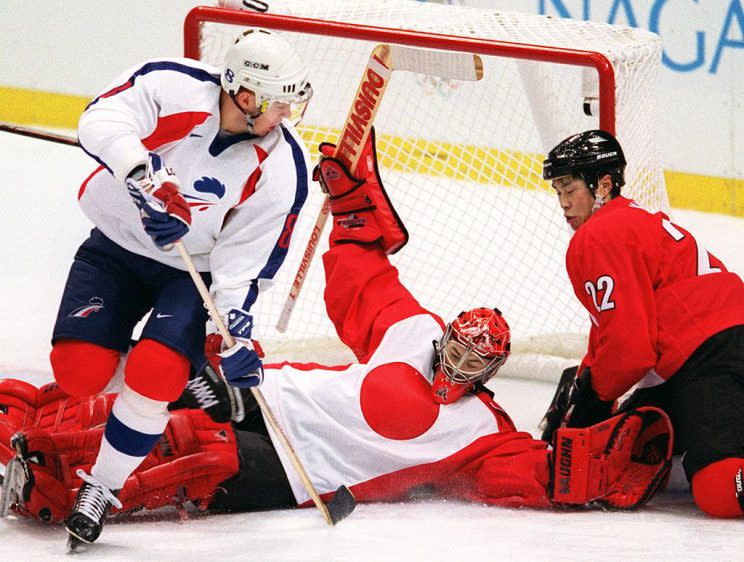 French forward Arnaud Briand (L) looks on as Japanese goalkeeper Dusty Imoo falls onto teammate Makoto Kawahira (R) during their men preliminary match at the Nagano Winter Olympics 09 February. The match is at a 2-2 draw in the third period. AFP PHOTO/ROBERT SULLIVAN / AFP / ROBERT SULLIVAN (Photo credit should read ROBERT SULLIVAN/AFP/Getty Images)