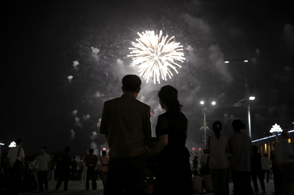 A North Korean couple is silhouetted against a fireworks explosion, Sunday, July 27, 2014 in central Pyongyang, North Korea. North Koreans gathered at Kim Il Sung Square to watch a fireworks display as part of celebrations for the 61st anniversary of the armistice that ended the Korean War.(AP Photo/Wong Maye-E)