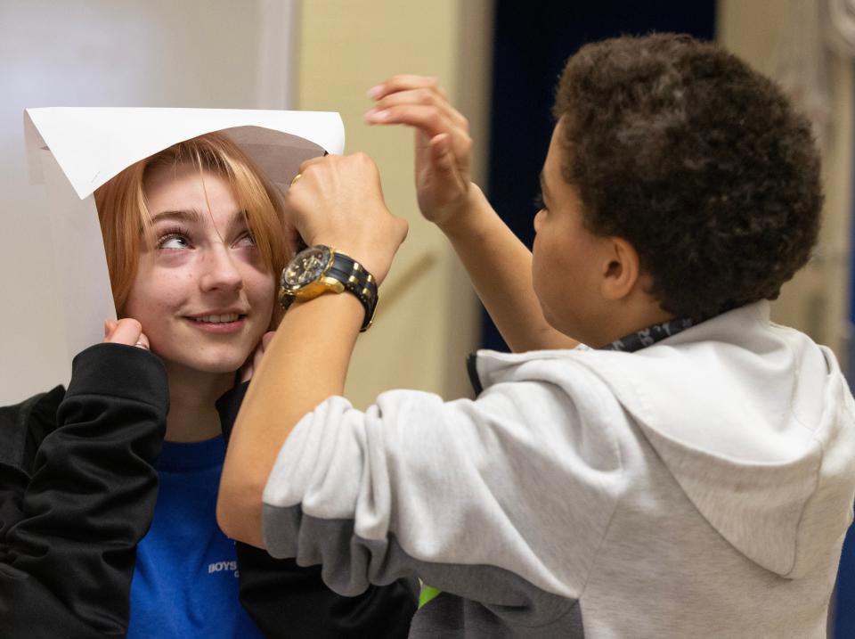 Massillon Boys and Girls Club employee Emilee Keehn helps club member Tracy Fields, 13, make a paper war helmet as an art project at the club.