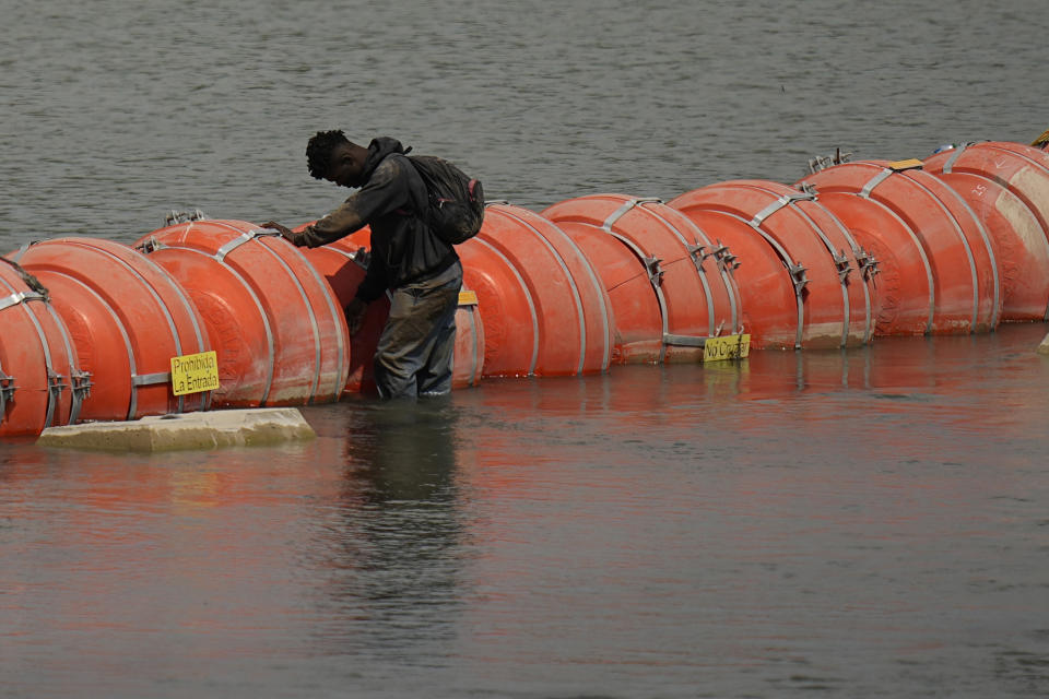 A migrant from Columbia stands at a floating buoy barrier as he looks to cross the Rio Grande from Mexico into the U.S., Monday, Aug. 21, 2023, in Eagle Pass, Texas. (AP Photo/Eric Gay)