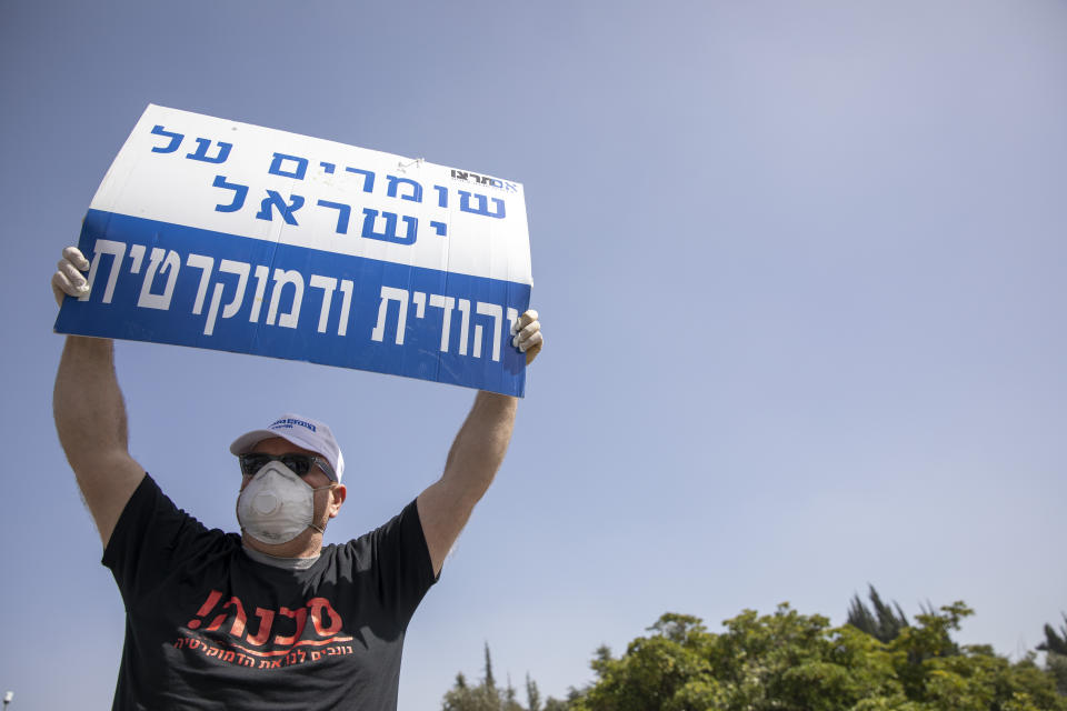 An Israeli supporter of Prime Minister Benjamin Netanyahu holds a sign that reads, "Keeping Israel Jewish and democratic," during a protest in front of Israel's Supreme Court, in Jerusalem, Tuesday, March 24, 2020. Israel appeared on the verge of a constitutional crisis Tuesday as top members of Benjamin Netanyahu's Likud urged their party colleague and parliament speaker to defy a Supreme Court order to hold an election for the prime minister's successor. (AP Photo/Ariel Schalit)