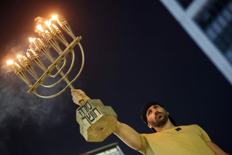 A protester carries a menorah as relatives and supporters of Israeli hostages in Gaza demonstrate in Tel Aviv (JACK GUEZ)